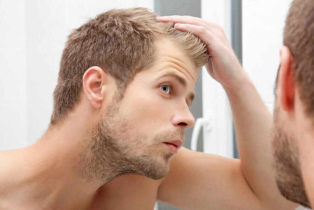 man looking at his hair in the mirror